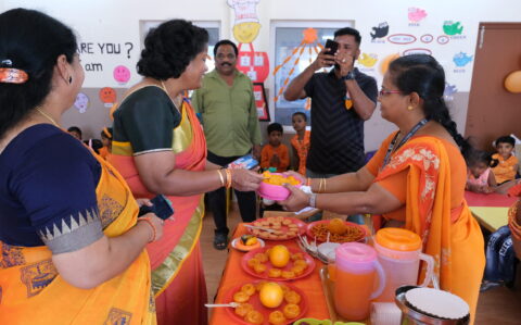 Principal Tasting Orange colour Food at Orange Day at RISHS International CBSE School Arcot