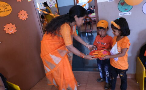 Students Receiving Orange Things From Teacher in Orange Day at RISHS International CBSE School Arcot